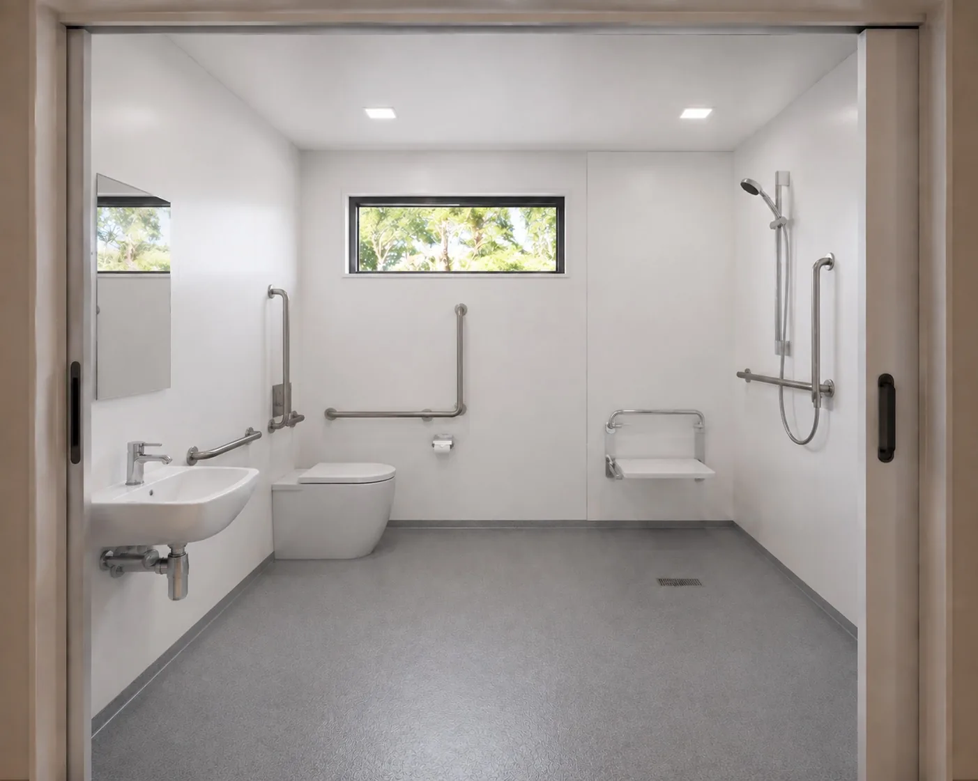 Accessible bathroom interior showing hobless shower, fold-down seat, toilet, basin and grab rail clearances