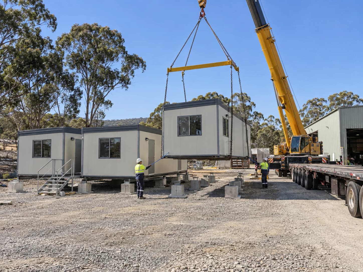 Crane lowering a prefab module onto prepared site footings
