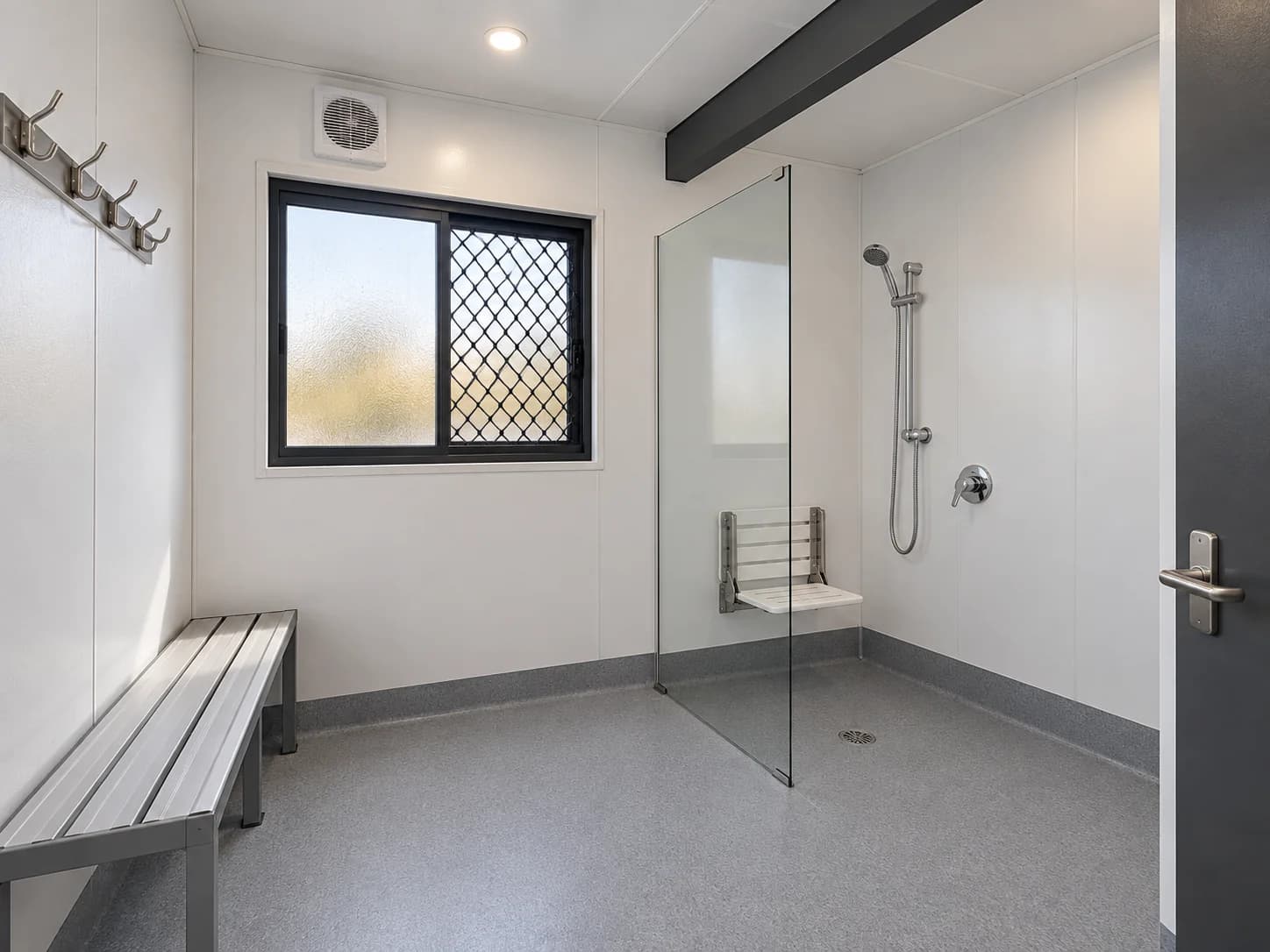 Prefab shower room with fold-down seat, handheld shower and bench